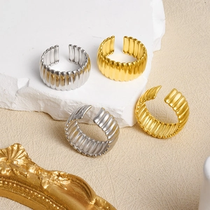 Detailed shot of pleated gold and silver stainless steel rings on a white textured stone
