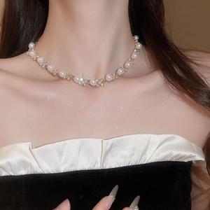 Dettaglio della collana con perle bianche e diamanti scintillanti su catena d'oro