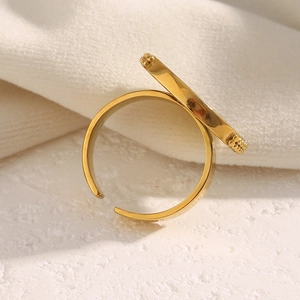 Detailed view of an 18K gold plated open ring with textured bar accent on white fabric