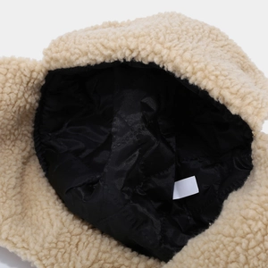 Detail view of beige fleece earflap hat with black quilted lining and soft texture