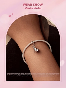 Close-up of a silver charm bracelet with a detailed ballerina pendant worn on a wrist