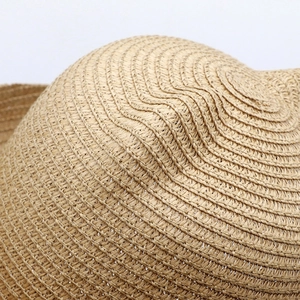 Close-up detail of the dense circular weave and natural fiber texture of the straw hat