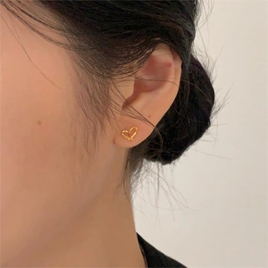 Detail of minimalist gold heart stud earring worn on model for a natural elegant look