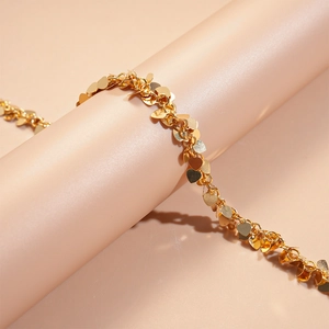 Detailed view of a gold-toned metallic necklace with delicate heart-shaped sequins