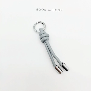 Detail of grey-blue braided leather keychain with silver spring clasp and metal caps