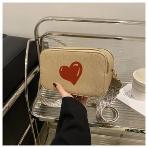 Detail of off-white crossbody bag with red heart print and textured wide strap
