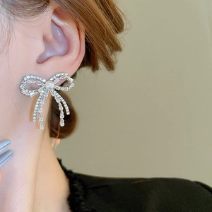 Close-up of bow knot stud earrings with pavé crystals and centered faux pearl on model