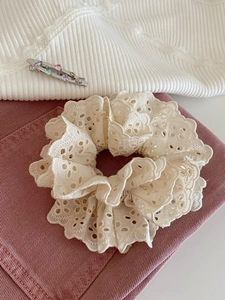 Gros plan du chouchou en dentelle crème double épaisseur avec motifs floraux crochetés