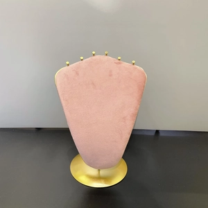 Pink velvet necklace display stand with six gold metal hooks on a round base