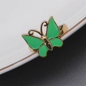 Detail view of a gold-plated butterfly ring with green enamel finish on white plate