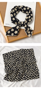Detailed view of square silk scarf with beige floral pattern on black fabric