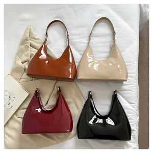 Glossy patent leather baguette bags in four colors arranged on a minimalist white backdrop