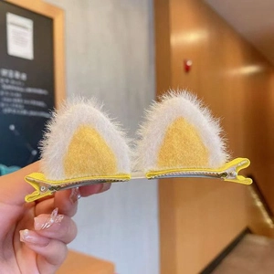 Detail of yellow plush cat ear hair clips with white faux fur on silver duckbill clips