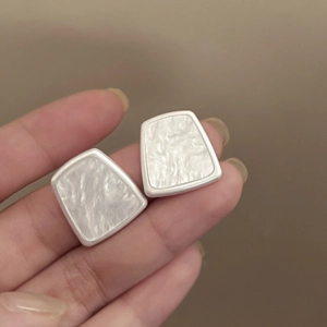 Detail of geometric resin earrings with white pearl texture and silver metal border