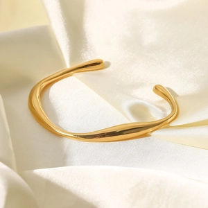 Bracciale rigido dorato 18 carats dal design ondulato su elegante tessuto in seta beige