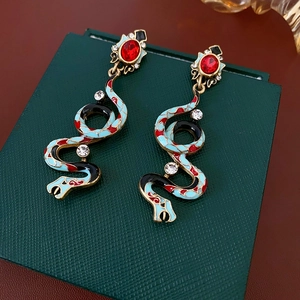 Macro shot of vintage snake earrings with colorful enamel and inset rhinestones on a box
