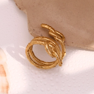 Détail d'une bague à triple nœud plaquée or avec des gouttes d'eau sur une pierre texturée