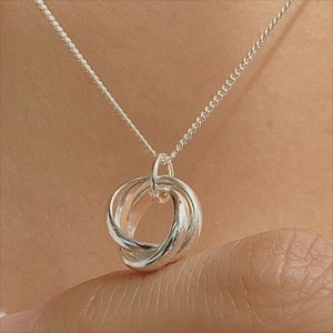 Handheld view of a 925 sterling silver interlocking triple ring pendant necklace