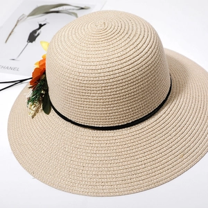 Detail of beige straw sun hat featuring vibrant orange floral accents and woven texture