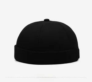 Détail du bonnet docker noir en coton avec un logo métallique vintage sur le bord replié
