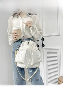 Close-up of white nylon bucket bag featuring black drawstring toggle and metal hardware