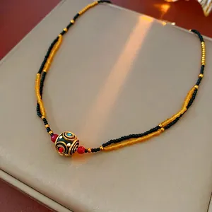 Collana a doppio filo di perline con ciondolo etnico dorato su pelle color champagne