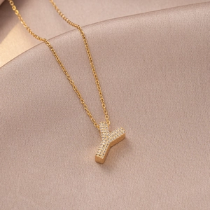 Macro detail of golden letter Y necklace pendant with sparkling white zircons on silk