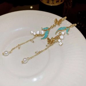Detail of long drop earrings featuring bamboo flower, lily of the valley and pearls