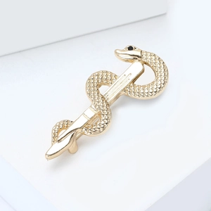 Macro detail of golden snake brooch with scale texture and black stone eye inlay