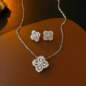 Close-up of zircon clover necklace and earrings set on premium brown leather background