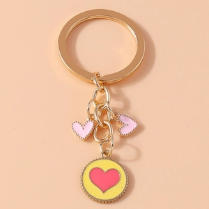Macro view of gold keychain with pink heart charms and round yellow enamel pendant