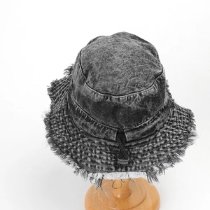 Detail of dark grey washed denim bucket hat with frayed edges and adjustable drawstring