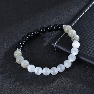 Detail of 8mm moonstone and obsidian beaded bracelet on a dark textured background