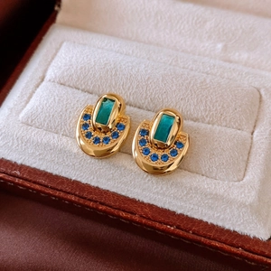Vue macro de boucles d'oreilles ovales plaquées or 18K avec gemme verte et pierres bleues