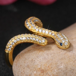 Macro de anillo de serpiente dorado con circonitas blancas y ojos de piedras azules en piedra