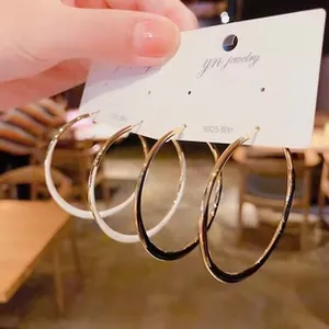 Close-up of S925 silver needle hoop earrings in black, cream white and gold finishes