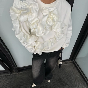 Détail d'un sweat-shirt blanc avec des volants en satin et un tissu en coton de qualité