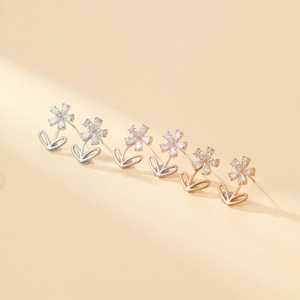 Close-up of snowflake stud earrings in silver, gold and rose gold with zircon stones
