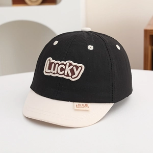 Close-up of Lucky embroidery and fabric texture on a kids baseball cap in black and beige