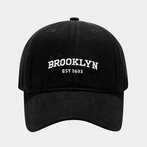 Close-up of white Brooklyn embroidery and stitching on black cotton baseball cap