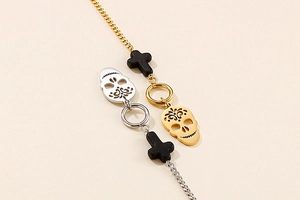 Detail of skull pendants and cross bead on mixed gold and silver stainless steel chain