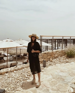 Outdoor vacation style with a woven straw hat, black lace dress, and chic platform sandals