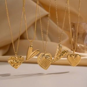 Colliers pendentifs coeur dorés classiques aux textures variées sur fond de soie élégant