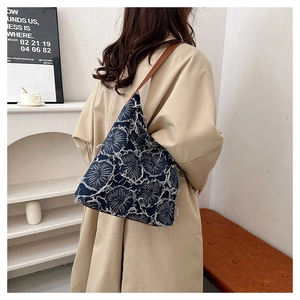Detail of vintage denim tote bag with white floral pattern and brown shoulder strap