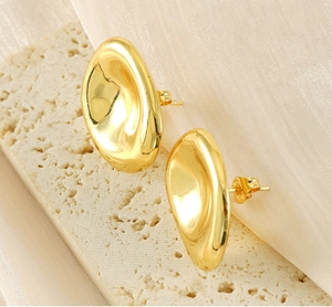 Close-up of irregular oval 18K gold plated stainless steel stud earrings on silk