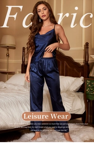 Detail of dark blue satin camisole top and loose pajamas set in a cozy bedroom setting
