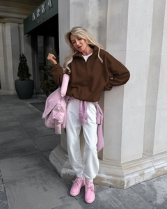 Detail of a brown sherpa fleece pullover styled with a pink checkered shirt around the waist