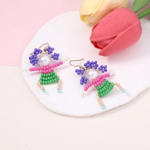 Macro shot of handmade beaded character earrings with colorful beads on a white tray