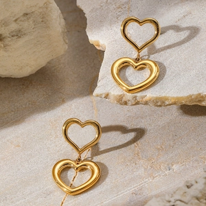 Macro shot of 18K gold plated double heart earrings on a minimalist natural stone background