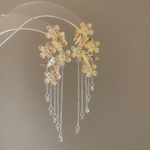 Detail of gold flower and butterfly earrings with long metal chain tassels and crystal drops